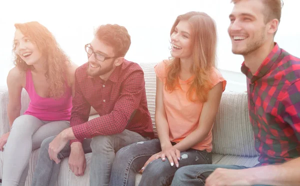 Grupo de jóvenes sonrientes sentados en el sofá — Foto de Stock