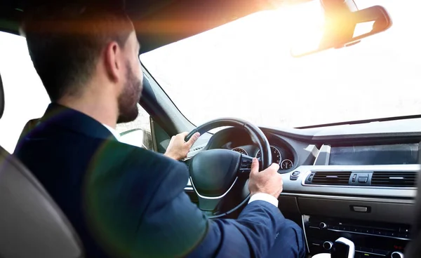 businessman sits at the wheel in his car and looks at the road