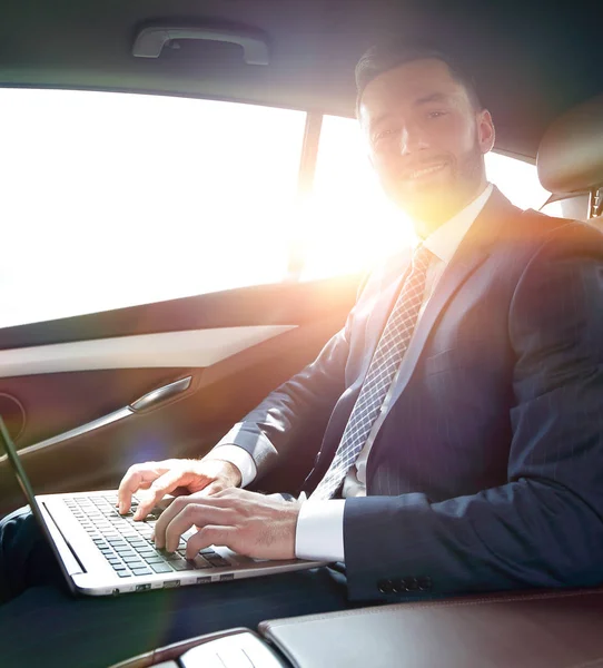 Mladá podnikatelka pracující na svém laptopu, zatímco sedí v autě — Stock fotografie