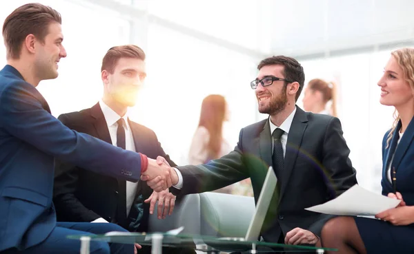 Partner bei Vertragsabschluss und Händeschütteln im Beisein von Teammitgliedern — Stockfoto