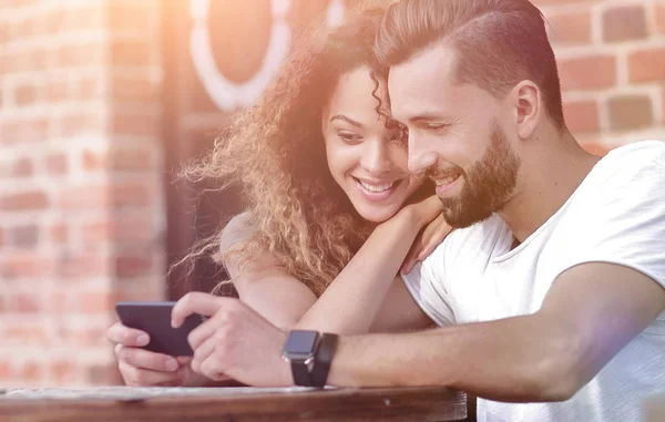 Happy loving  couple using a smartphone sitting in terrace — Stock Photo, Image