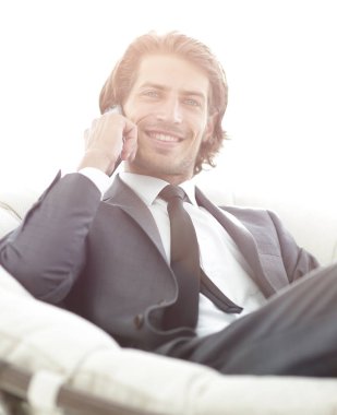 iş adamı bir comforta otururken Smartphone'da konuşuyor