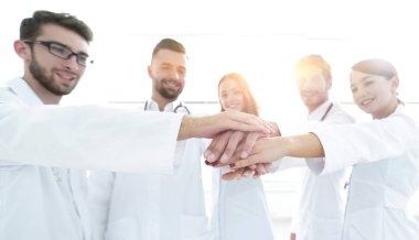 Doktorlar ve hemşireler tıbbi bir ekipte el ele tutuşuyorlar.