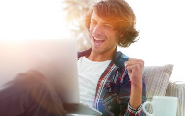 bir sehpa oturan bir dizüstü bilgisayar ile çok mutlu adam.