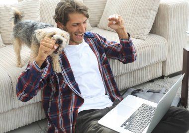 sevindirici ve yakın oturma odasında kanepede oturan ellerini yükselterek mutlu adam.