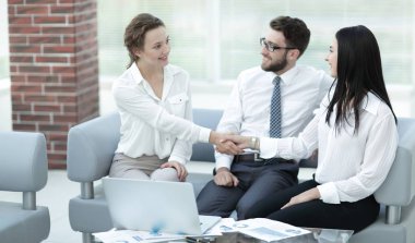 Ofis lobisinde yönetici ve müşterinin el sıkışması.