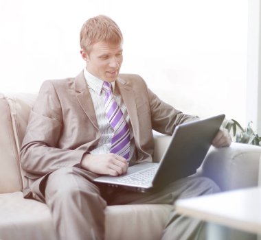 Laptop ile çalışma ofis lobisinde oturan genç işadamı