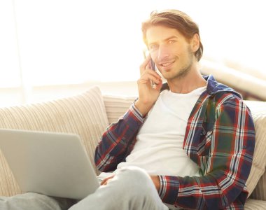 cep telefonu üzerinde konuşurken laptop ile ciddi genç adam