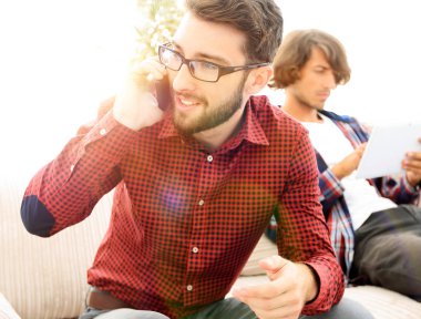 adam kanepede oturan smartphone cep telefonu ile konuşmak.