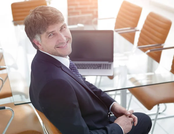 Gerente sonriente sentado en el escritorio en la sala de reuniones . — Foto de Stock