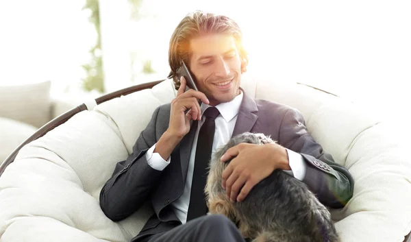 businessman is holding his pet and talking on a smartphone