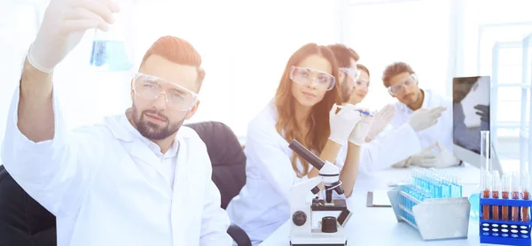 Биохимик с фляжкой Петри сидит за столом — стоковое фото