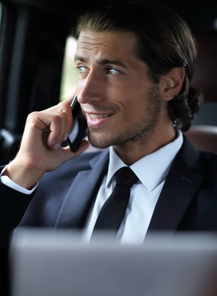 Uomo d'affari in macchina con un portatile che parla al telefono — Foto Stock
