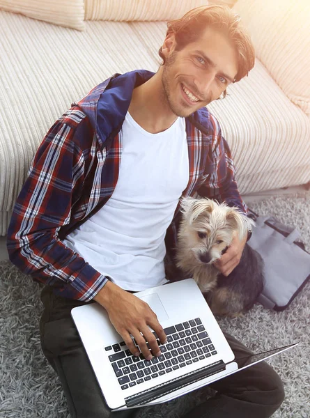 Bel ragazzo con il computer portatile abbracciare il suo cane e seduto vicino al co — Foto Stock