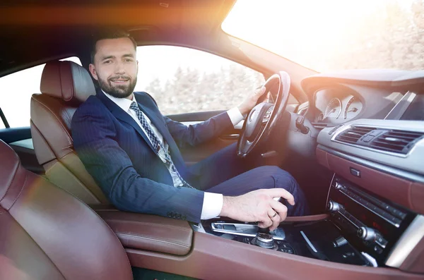 Vista dal lato uomo d'affari fiducioso siede al volante di un — Foto Stock