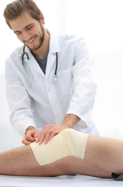 Doctor looking at the bandage on the patients leg — Stock Photo, Image