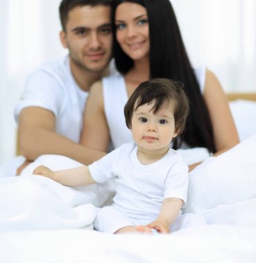 yatakta evde oturan neşeli bir aile portresi