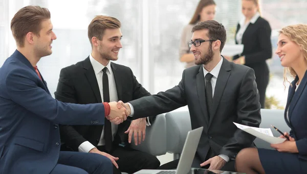 Partner che concludono un accordo e stringono la mano alla presenza dei membri del team — Foto Stock