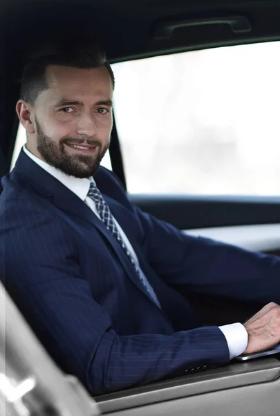 Close-up of a businessman with a laptop sitting in the car — Stock Photo, Image