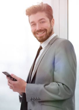 Takım elbiseli şık adam telefonla bilgi okuyor.