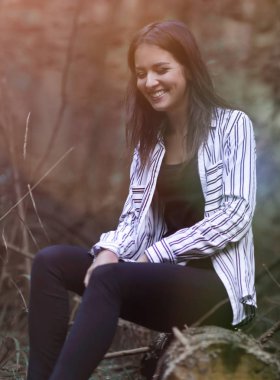 Ormanın içinde bir günlük üzerinde oturan genç kadın.