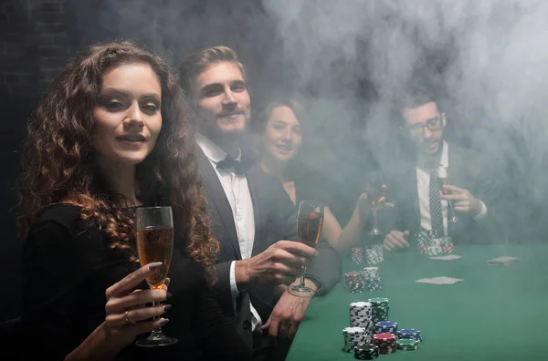 Groep vrienden zitten op de speeltafel in casino — Stockfoto