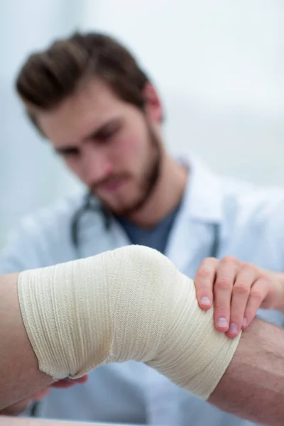 Traumatologista examinando a bandagem em seu joelho . — Fotografia de Stock