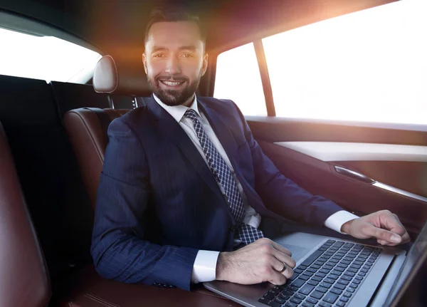 Uomo di successo che lavora con il computer portatile seduto in auto — Foto Stock