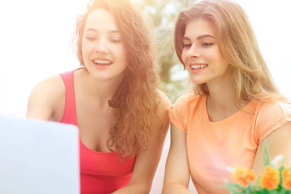 Zwei Studentinnen schauen auf den Laptop-Bildschirm, während sie auf der Couch sitzen. — Stockfoto
