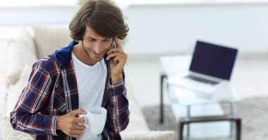 güzel bir fincan adamla bir dizüstü bilgisayar önünde oturur.