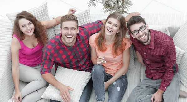 Quatro amigos felizes rindo enquanto sentados no sofá — Fotografia de Stock