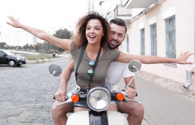 Güzel genç bir çift bir scooter sürme sırasında gülümsüyor
