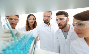 arka plan görüntüsü sıvı cam tüp içinde eğitim microbiologists oluşan bir gruptur.