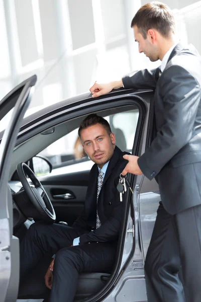 Biznesmenem, odebrania kluczy do samochodu od sprzedawcy w salonie — Zdjęcie stockowe