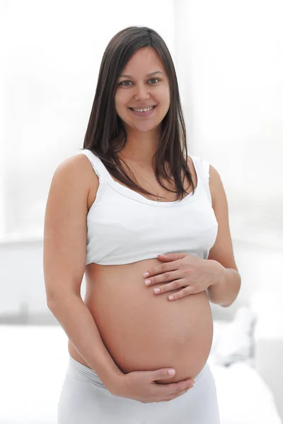 Portret van jonge zwangere vrouw op een lichte achtergrond. — Stockfoto