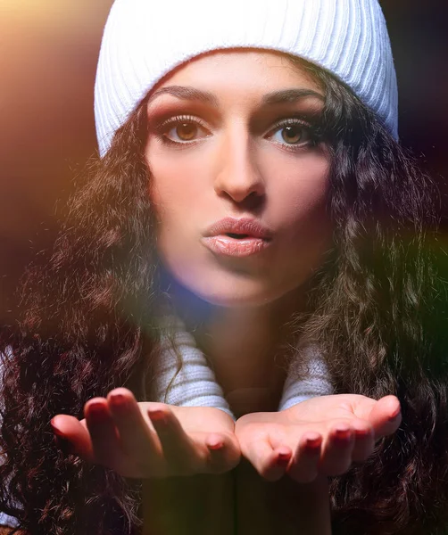 Retrato de uma menina em um chapéu de malha branco envia um beijo — Fotografia de Stock