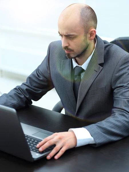 Serio uomo d'affari che lavora su laptop seduto alla scrivania — Foto Stock