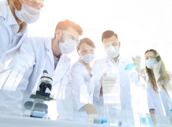 ученые работают с пробирками и микроскопом в лаборатории
