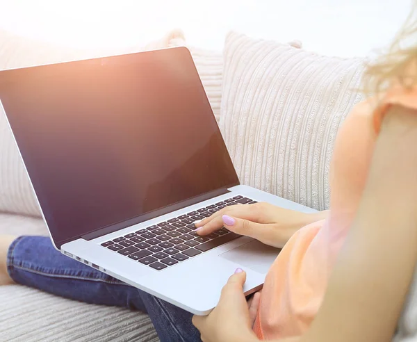 Jovem mulher trabalhando com laptop sentado no sofá — Fotografia de Stock