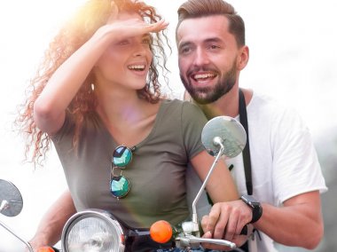 Güzel genç bir çift bir scooter sürme sırasında gülümsüyor