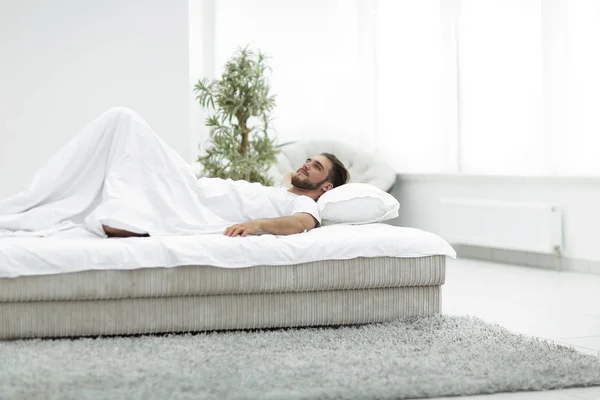 Ένας άνθρωπος κουρασμένος, ακουμπά σε ένα άνετο κρεβάτι — Φωτογραφία Αρχείου