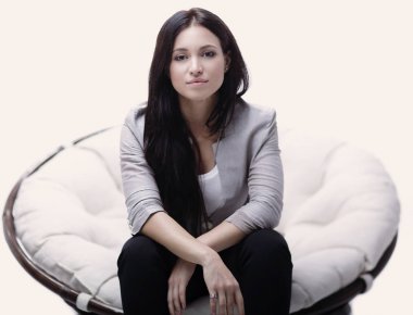 Genç kadın bir yuvarlak rahat yumuşak büyük sandalyede oturuyor.