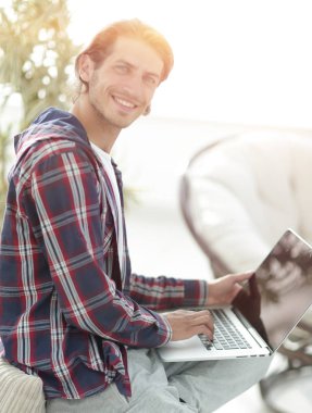 dizüstü bilgisayarda çalışan ve kameraya bakarak şık genç adam