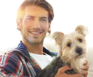 gülümseyen bir adam la otururken köpeğini okşayarak Close-Up