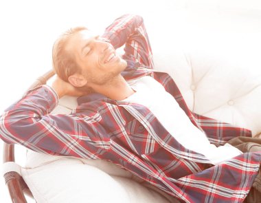 Modern adam büyük bir rahat sandalyede oturuyor dinleniyor. yan görünüm.