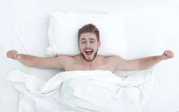 Pemandangan atas. Pria bahagia terbangun di tempat tidur yang nyaman — Stok Foto