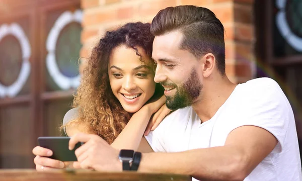 Feliz pareja amorosa usando un teléfono inteligente sentado en la terraza — Foto de Stock