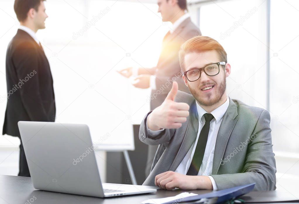 Manager sitting at his Desk and showing thumbs up