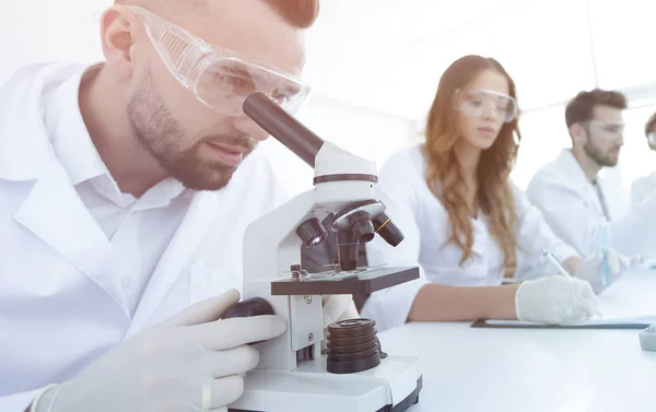 Técnico de laboratorio masculino que mira muestras en el microscopio — Foto de Stock