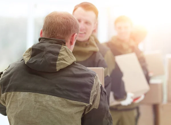 Happy male movers in uniform carrying boxes — Stock Photo, Image